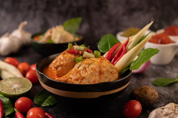 chicken curry in a bowl with lemongrass, kaffir lime leaves, tomatoes, lemon, and garlic