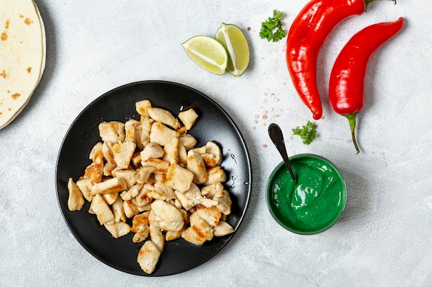 Foto gratuita piatto di pollo vicino a peperoni, salsa verde e lime a fette