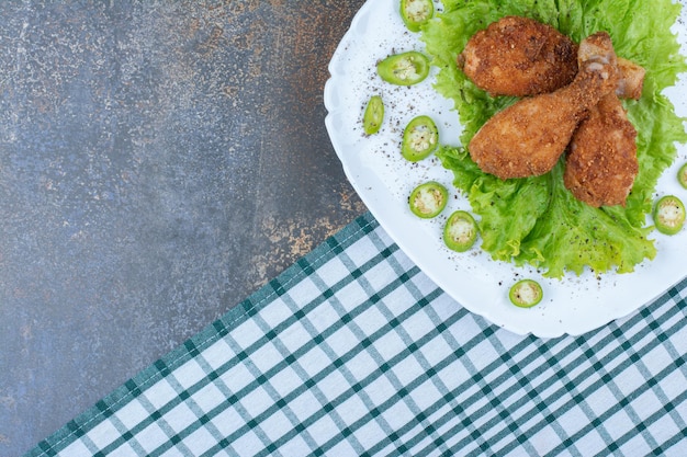 Chicken drumsticks with pepper and lettuce on white plate. High quality photo