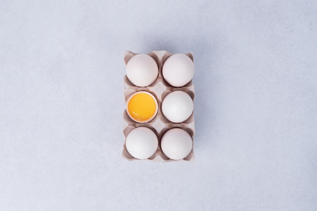 Free photo chicken eggs in paper container on white surface.