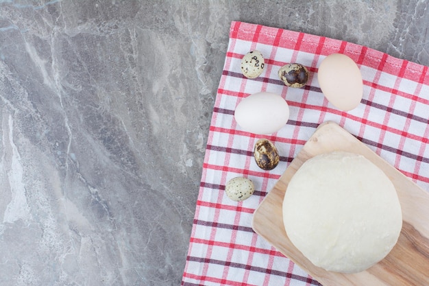Chicken eggs with quail eggs and dough on tablecloth. High quality photo