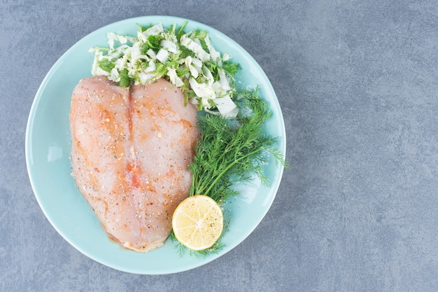 Free photo chicken fillet and lemon on blue plate.