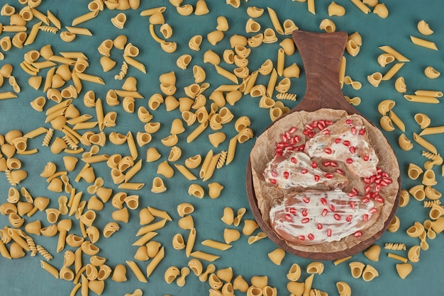 Foto gratuita filetto di pollo su una tavola di legno con spezie e pasta.