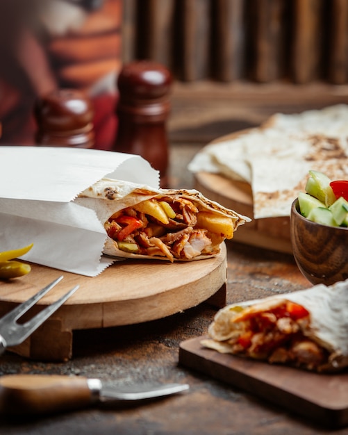 Chicken flatbread wrap with fries, tomato, prickles in takeaway paper bag