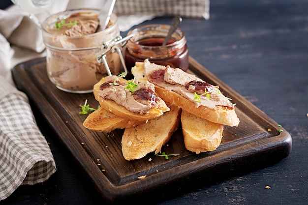 Chicken homemade liver paste in glass jar with toasts and lingonberry jam with chili