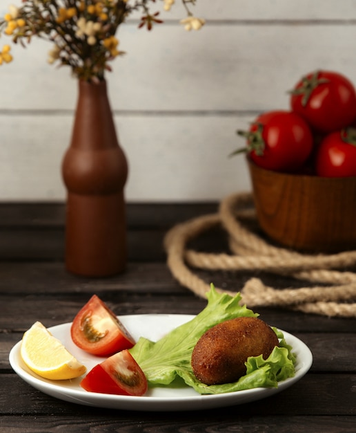 Chicken Ðºiev a slice of lemon and tomato on a wooden table