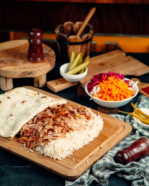 Chicken kebab slices served with rice and flatbread places on serving board