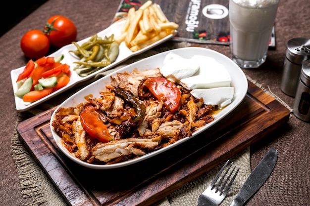 Chicken kebab with tomato sauce served with yogurt fries pickles and vegetables