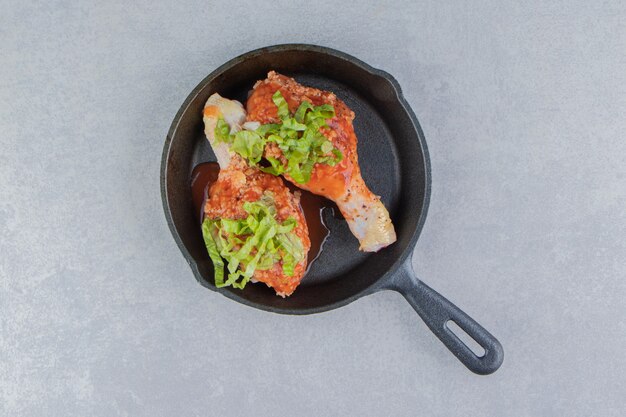 Chicken leg and green on the boiler, on the white surface