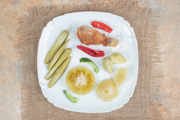 하얀 접시에 다양한 피클을 곁들인 닭 다리 무료 사진