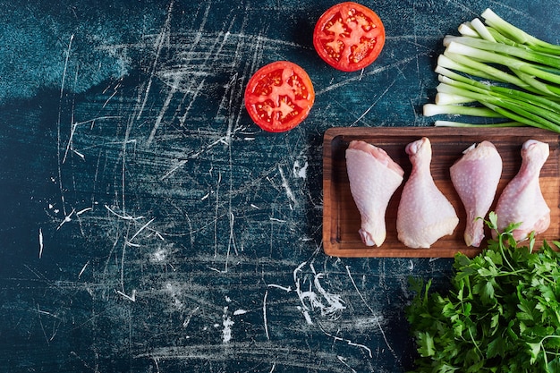 Free photo chicken legs on a wooden board .