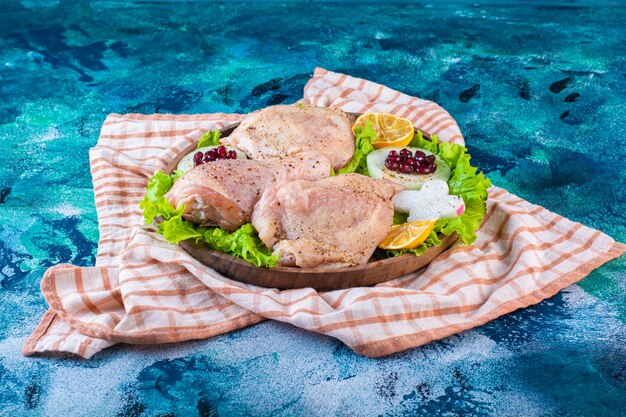 Chicken meat, lemon, pomegranate arils on a wooden plate on the tea towel