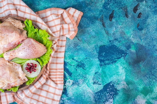 Chicken meat, lemon, pomegranate arils on a wooden plate on the tea towel