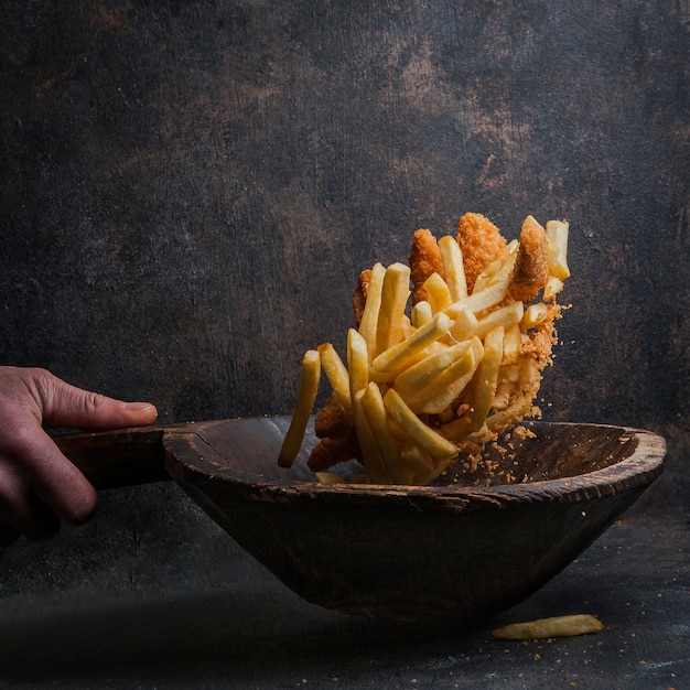 chicken nuggets with french fries and human hand in fly