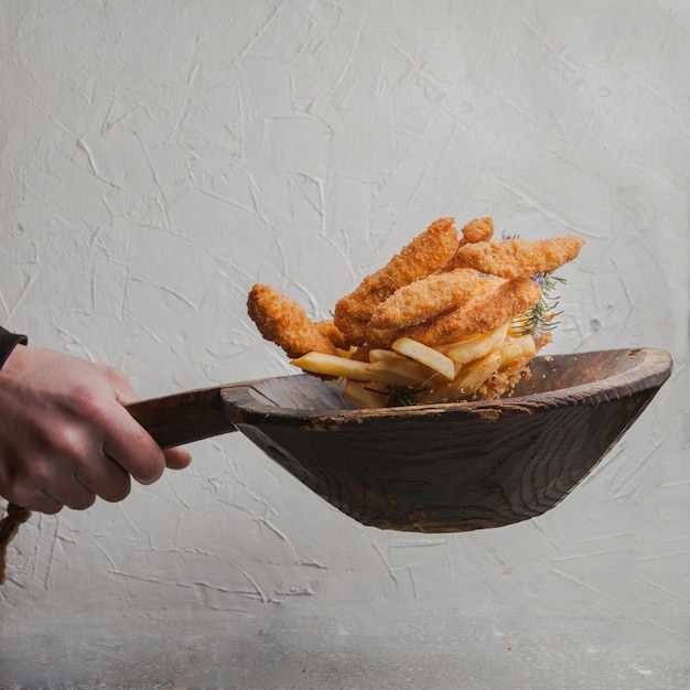 Free photo chicken nuggets with french fries and human hand in fly