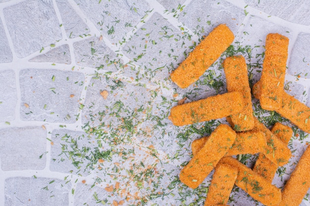 Chicken nuggets with herbs and spices on grey.