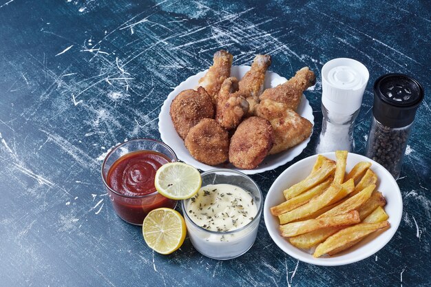 Chicken pieces with potatoes in a white plate.