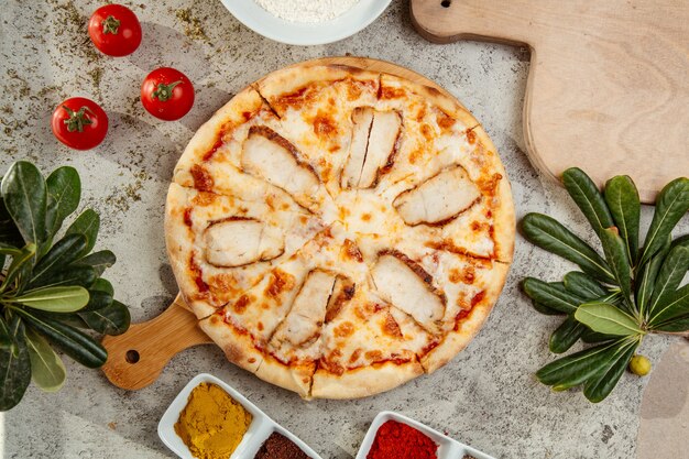 Chicken pizza and some tomatoes on the table