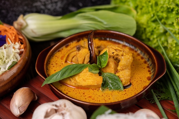 Chicken red curry in a bowl with dried chilies, basil, cucumber and long beans