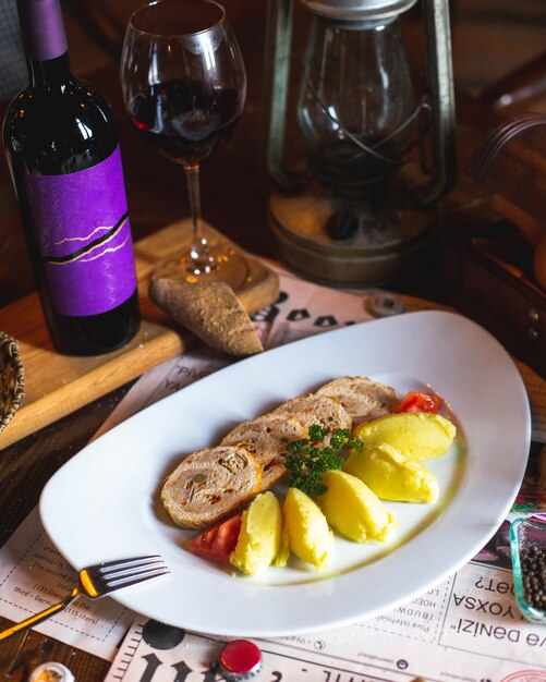 Chicken roll served with mashed potatoes, greens and tomato slices