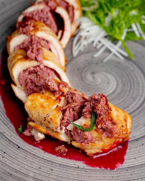 Free photo chicken roll stuffed with meat and served with greens