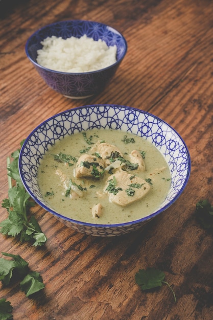 Chicken soup and a bowl of rice on a wooden surface