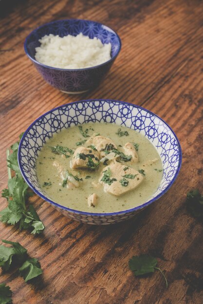 Chicken soup and a bowl of rice on a wooden surface