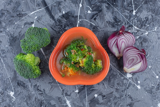 Foto gratuita zuppa di pollo, broccoli e cipolla sulla superficie blu