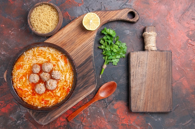 Zuppa di pollo con noodles a bordo e pasta cruda, verdure al limone e tagliere su sfondo scuro