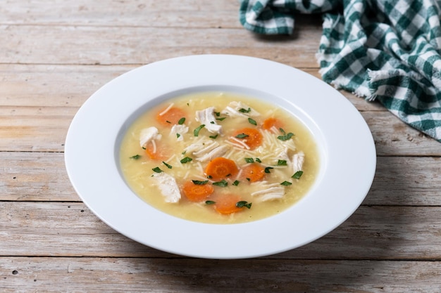 Foto gratuita zuppa di pollo con verdure su tavolo di legno