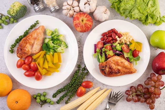 Chicken steak topped with white sesame, peas, tomatoes, broccoli and pumpkin in a white plate.