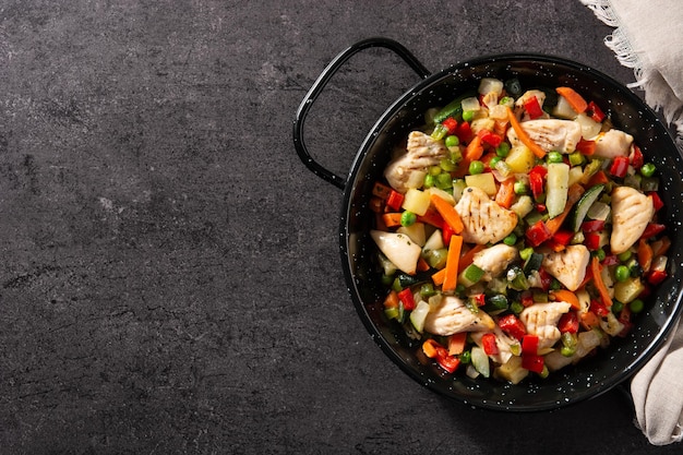 Chicken stir fry and vegetables on black stone background