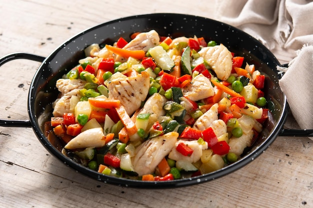 Chicken stir fry and vegetables on wooden table