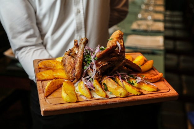 Chicken tabaka on the wooden board with homemade potato onion greens side view