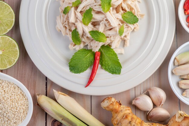 The chicken that is bordered is cooked and placed in a white plate along with mint leaves.