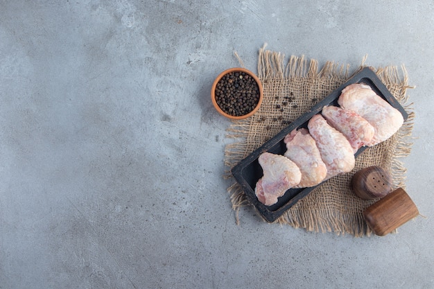 Chicken wings on a board on a burlap napkin, on the marble background. 