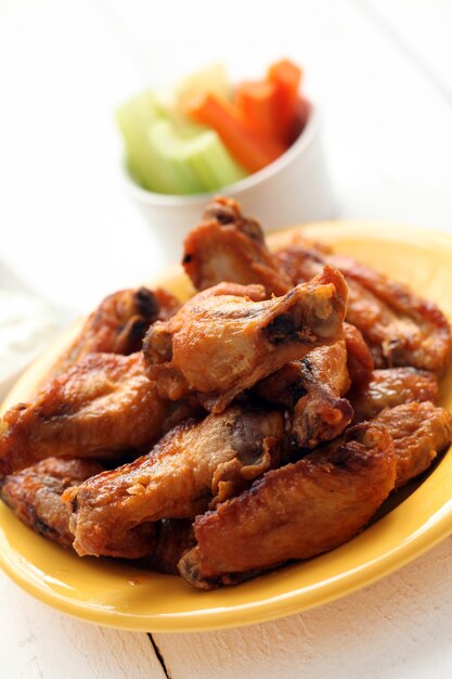 Chicken wings in bowl with vegetables