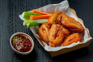 Free photo chicken wings in paper box on a black