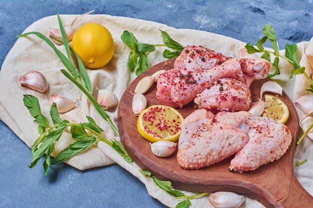 Chicken wings with lemon on a wooden board on blue