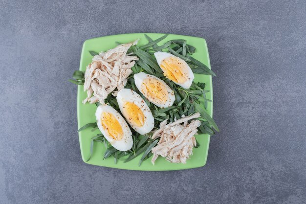 Chicken with boiled eggs on green plate.