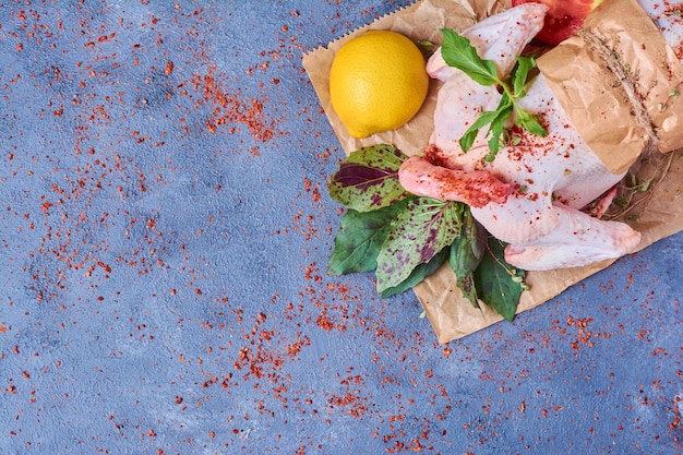 Foto gratuita pollo con spezie su una tavola di legno sul blu