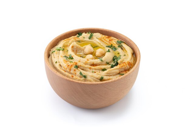 Chickpea hummus in a wooden bowl garnished with parsley paprika and olive oil isolated on white background Close up