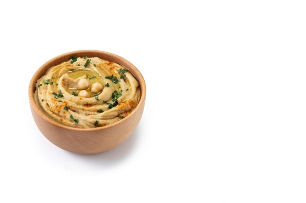 Chickpea hummus in a wooden bowl garnished with parsley paprika and olive oil isolated on white background