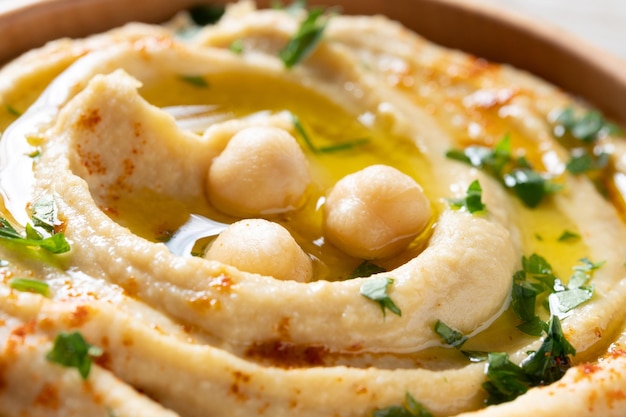 Hummus di ceci in una ciotola di legno guarnito con prezzemolo paprika e olio d'olivaxa