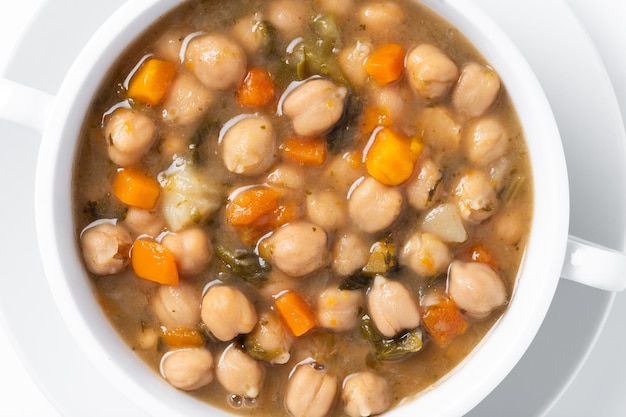 Chickpeas soup with vegetables in bowl isolated on white background