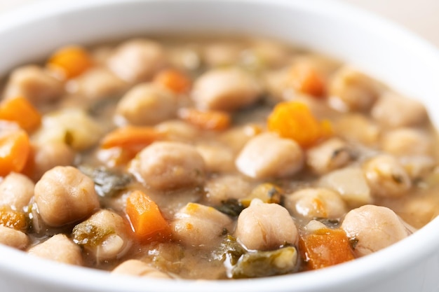 Chickpeas soup with vegetables in bowl on wooden table