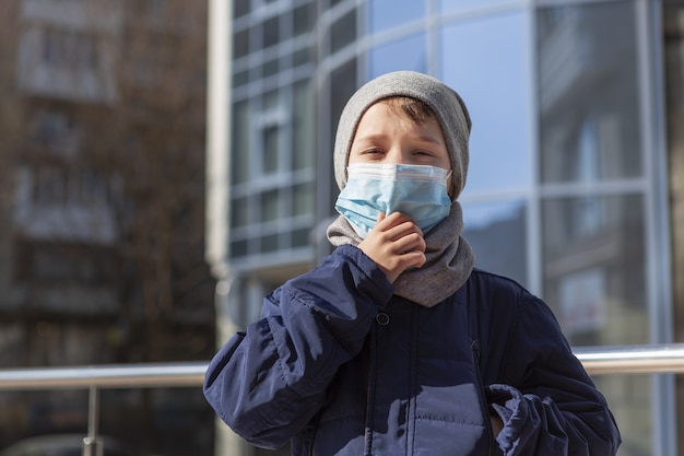 Child adjusting his medical mask outside