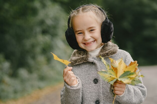 Child in a autumn park. Kid in a gray coat.