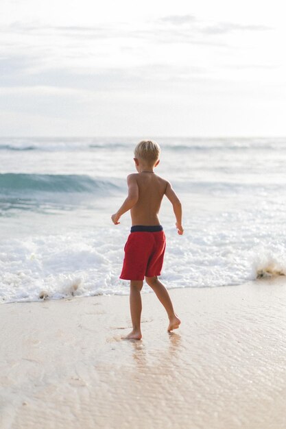 A child on the beach plays in the waves of the ocean. Boy on the ocean, happy childhood. tropical life.