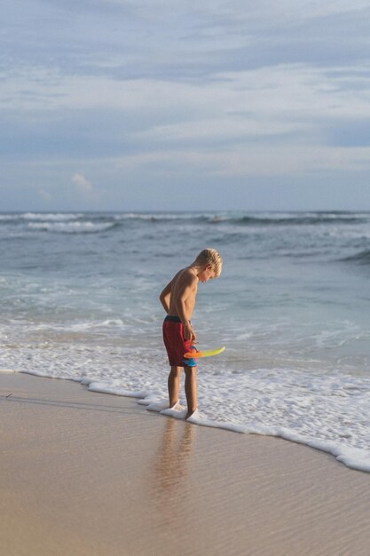 ビーチの子供は海の波で遊んでいます。海の少年、幸せな子供時代。トロピカルライフ。
